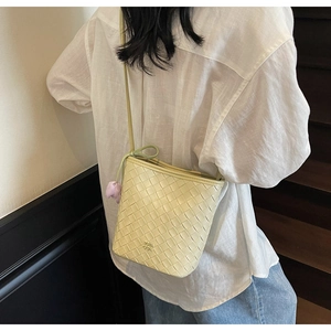 Detailed back view of a beige woven bucket bag with elegant rhombus texture and floral charm