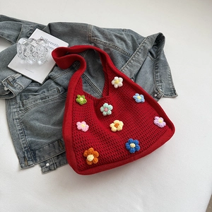 Detail of red handmade knit tote bag featuring colorful 3D floral crochet accents
