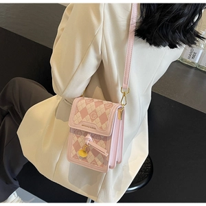 Detail of pink and white checkered mini bag with gold hardware worn over a white suit