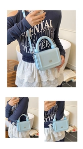 Detail of light blue lychee pattern leather bag with golden logo and tubular handle