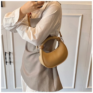 Detail view of light brown crescent underarm bag with decorative wooden beads and silver buckle