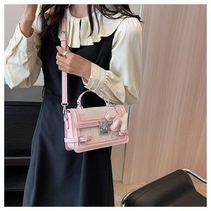 Detail of pink jacquard handbag with silver hardware and a cute white plush puppy charm