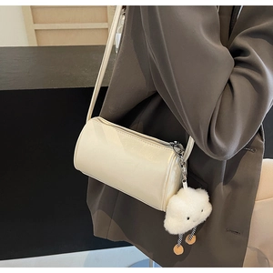 Detailansicht der cremefarbenen Zylindertasche mit Plüschwolken-Anhänger und Silber-Reißverschluss