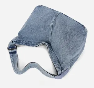 Détails du tissu en denim bleu délavé et des coutures d'un grand sac bandoulière style hobo