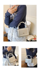 Detail view of silver textured leather underarm bag with thick handle and metal buckle