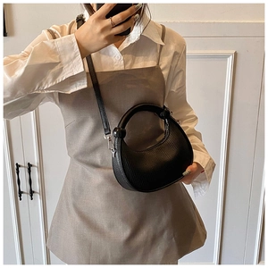 Close-up of black lizard pattern half-moon bag with round handle and metal strap buckle