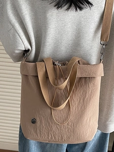 Khaki nylon drawstring tote bag with adjustable shoulder strap worn by a model