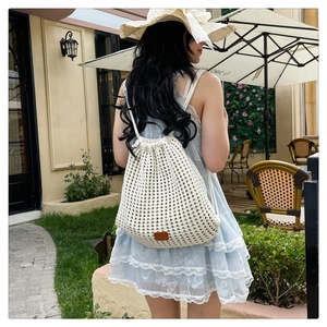 Detailed close-up of white crochet drawstring backpack with a brown leather logo patch