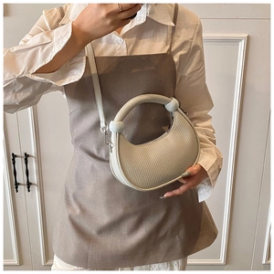Creamy white crescent handbag with round handle and litchi texture on a model side-carry