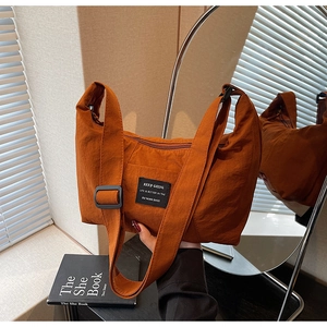 Detail of caramel nylon tote bag showing pleated texture and adjustable shoulder strap
