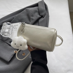 Detailansicht der cremefarbenen Zylindertasche mit glänzendem Leder und Wolkenanhänger