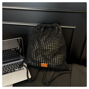 Macro detail of black mesh knit drawstring bag with brown leather label on the front