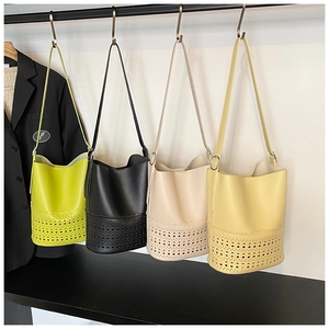 Detail view of multi-color cutout bucket bags featuring laser-cut hollow pattern