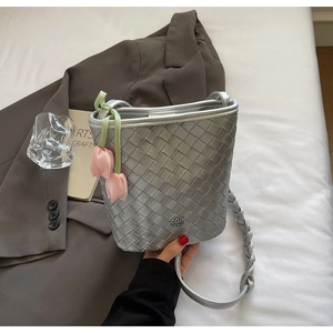 Detail of silver woven bucket bag featuring a pink tulip charm and metal logo brand