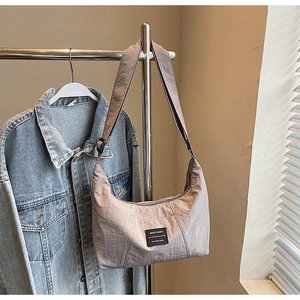 Close-up of mauve crescent tote bag hanging on a rack with natural light shadows