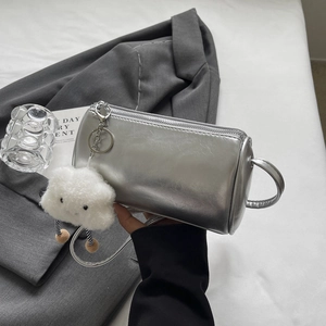 Detailansicht der silbernen Zylindertasche mit Metallic-Finish und Plüschanhänger