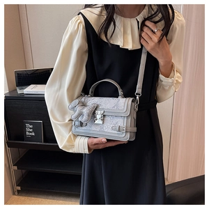 Detail of light blue floral jacquard handbag with metal turn-lock and cute bear charm