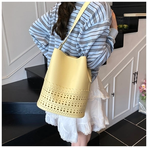 Detail of yellow laser-cut bucket bag with geometric patterns and adjustable strap
