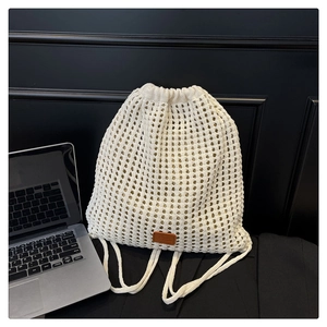 Close-up of cream woven drawstring backpack with large mesh texture and leather patch
