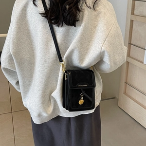 Elegant quilted black crossbody bag with gold chain strap shown on a model