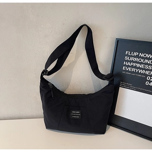 Close-up of black nylon crescent tote bag with adjustable wide strap and textile patch