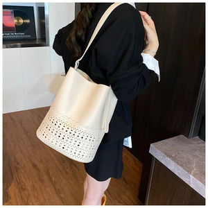 Detail of laser-cut geometric flower pattern on off-white bucket bag with wave edge