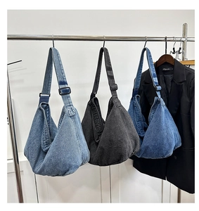 Drei Denim-Umhängetaschen in Hellblau, Dunkelblau und Schwarz an einer Kleiderstange