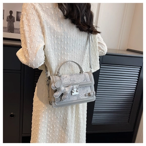 Detail of grey floral jacquard handbag with leather trim and animal charm pendant