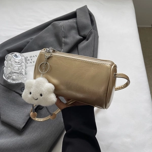 Detail einer metallisch goldenen Zylindertasche mit süßem weißem Plüschwolken-Anhänger