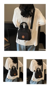 Detail view of black nylon crossbody bag with round logo, zipper pockets and top handle