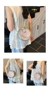 Détail d'un sac rond rose tressé avec bandoulière en perles et décoration en nœud
