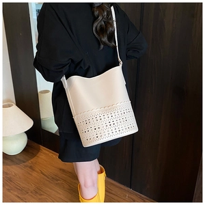 Close-up of cream white bucket bag featuring intricate hollow-out geometric laser cut patterns