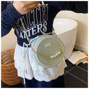 Détail du sac rond en paille avec cuir menthe, sangle en perles et chaîne dorée