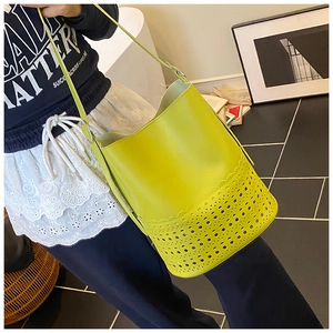 Detailed view of neon green bucket bag with hollow floral pattern and shoulder strap