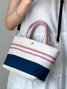 Canvas bucket bag with red checkered and blue stripes, featuring woven handles and strap