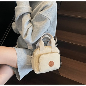 Detail view of stylish beige canvas crossbody bag featuring durable strap and front pocket