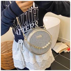 Détail du sac à bandoulière rond argenté avec texture tissée et chaîne à perles de luxe