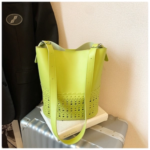 Detail view of neon green hollow bucket bag with intricate laser-cut floral patterns