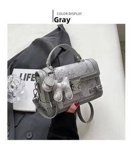 Close-up of grey handbag with elegant floral embroidery and silver dog charm pendant