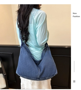 Detailansicht einer großen dunkelblauen Denim-Hobo-Tasche mit breitem Gurt am Model