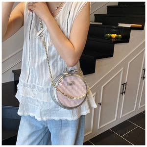Vue détaillée du sac rond rose tissé avec chaîne de perles et poignée en forme de nœud