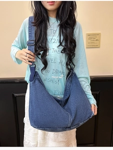 Detail der blauen Denim-Hobo-Tasche mit verstellbarem Riemen und Metallschnalle am Model