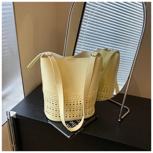 Detail view of the cream laser-cut hollow pattern on the bucket bag with adjustable strap