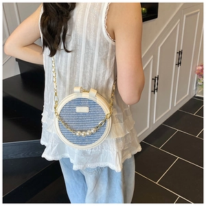 Détail du sac à bandoulière rond tissé avec motifs bleus et élégante chaîne de perles