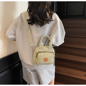 Back view of model carrying light green nylon crossbody bag on a wooden staircase