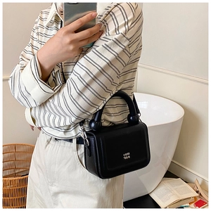 Detail of black leather crossbody bag featuring unique thick handle and logo branding