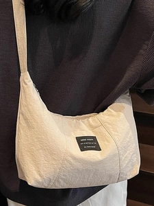Minimalist beige tote bag in wrinkled fabric texture worn by a model in a side view