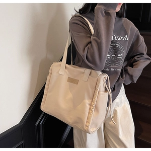 Detail view of large beige canvas tote bag with side drawstring and fashion logo