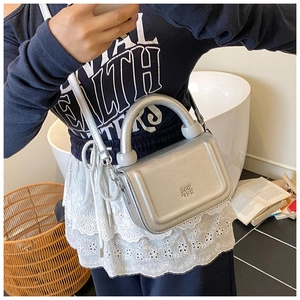 Silver grainy leather crossbody bag with thick handle shown in a daily lifestyle setting