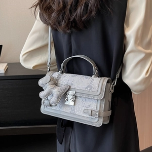 Gray jacquard crossbody bag with floral pattern and decorative teddy bear charm